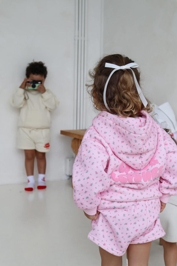 Back view of a girl in the pink floral hoodie and shorts set. Love & Leisure Kids Lounge Set in Floral Fantasy print by Skylaroseco