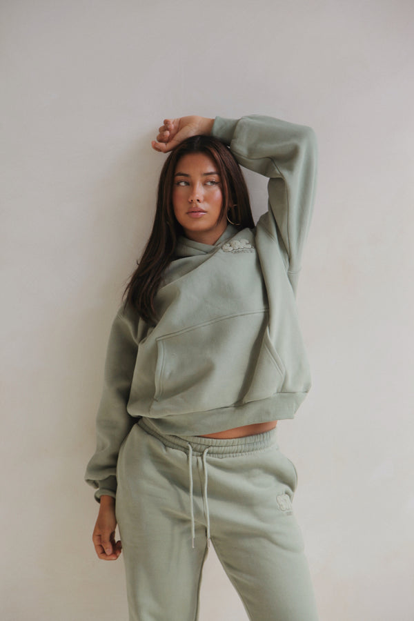 Woman standing in the sage hoodie and sweatpants set. Cosy Club 2.0 Adults Hoodie in Sage by Skylaroseco