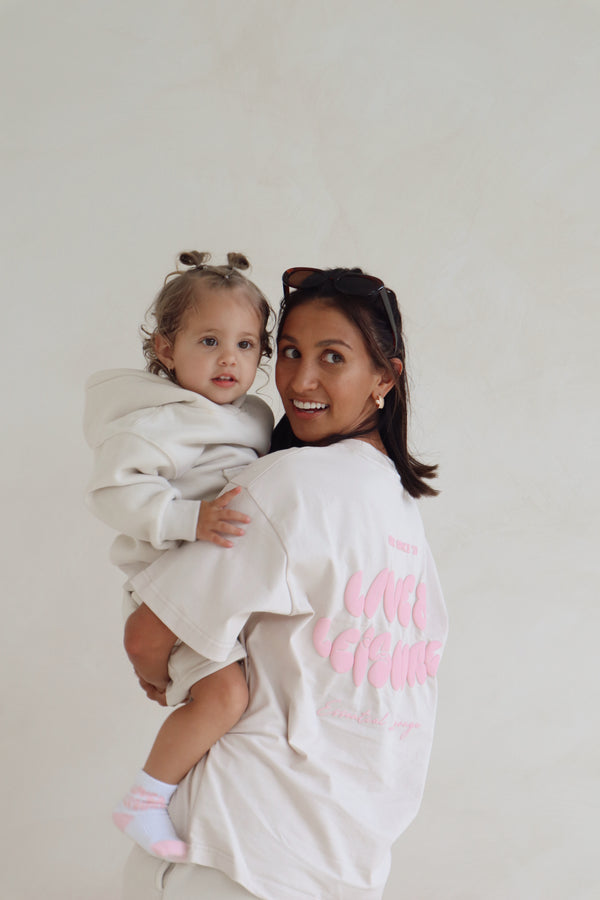 Mum holding her daughter, both in matching cream tees with pink puff print. Love & Leisure Adults Oversized Tee in Astro Candy by Skylaroseco