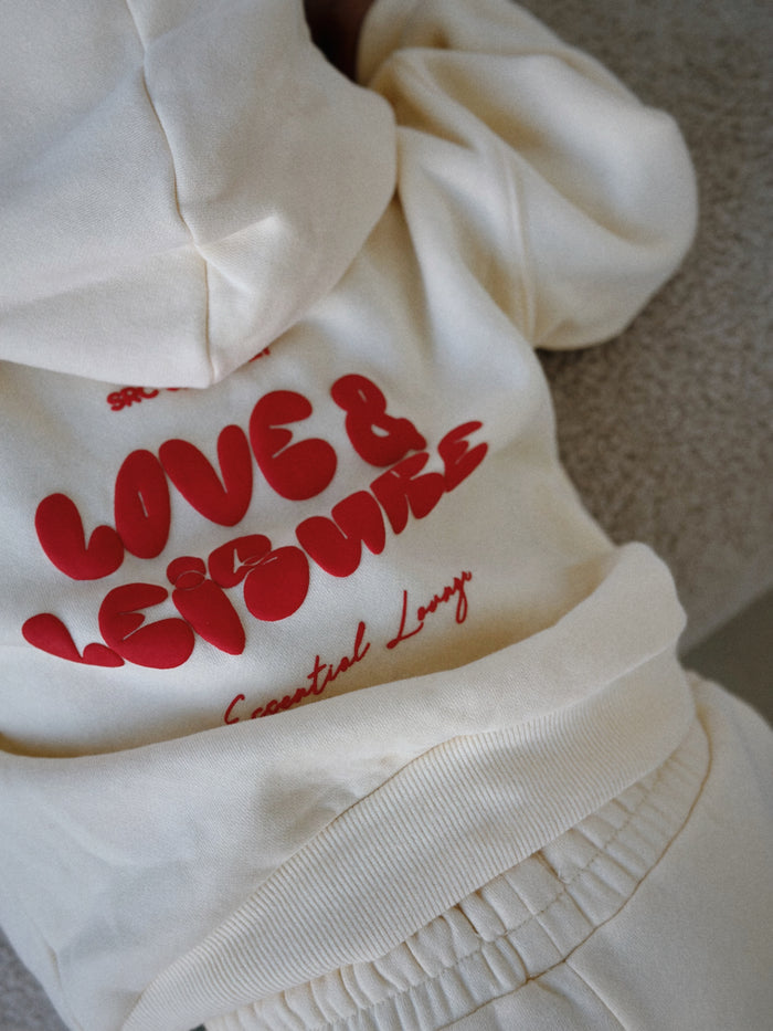 Close-up of the red Love & Leisure print on the cream kids hoodie. Love & Leisure Kids Lounge Set in Cherry Cream by Skylaroseco