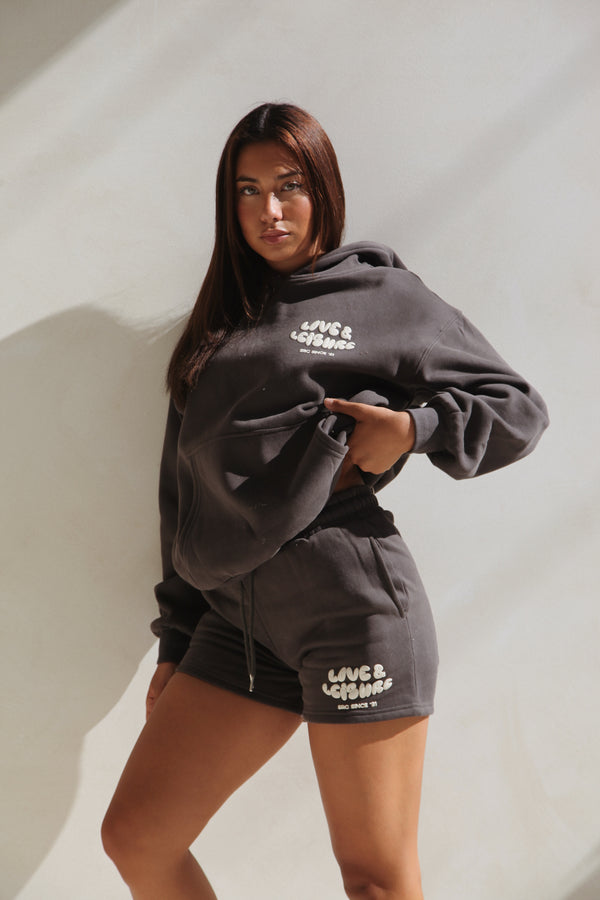 Woman standing in the charcoal hoodie and lounge shorts. Love & Leisure Adults Hoodie in Moondust by Skylaroseco