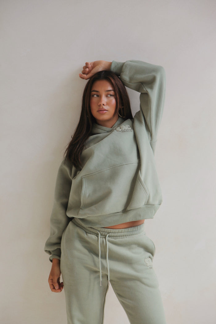 Woman standing in the sage hoodie and sweatpants set. Cosy Club 2.0 Adults Hoodie in Sage by Skylaroseco