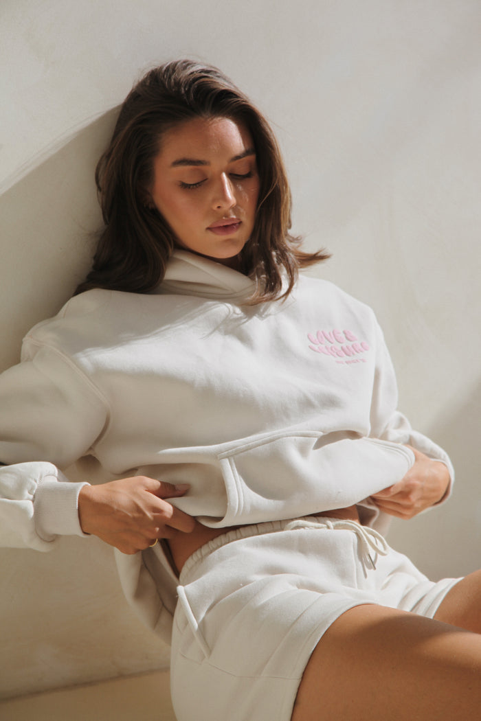 Woman seated in the lounge shorts with a matching cream hoodie. Love & Leisure Adults Lounge Shorts in Astro Candy by Skylaroseco
