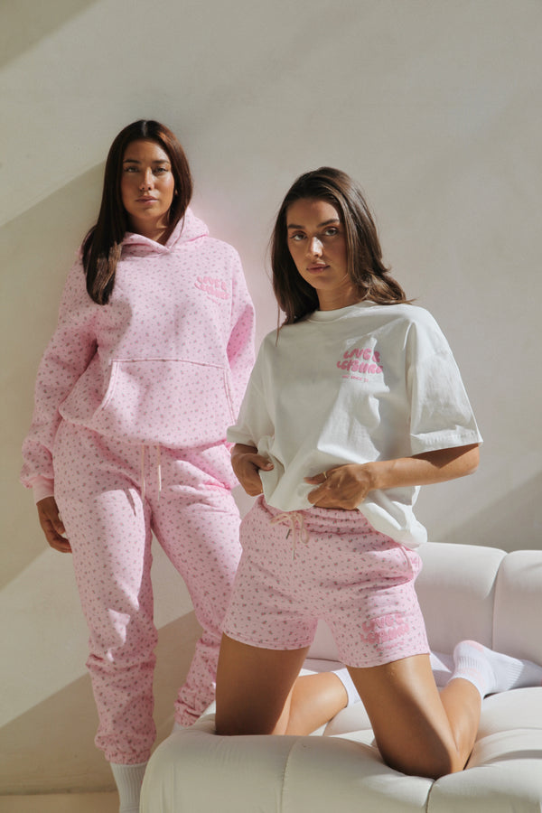 Two women in pink floral lounge pieces, one standing and one seated. Love & Leisure Adults Lounge Shorts in Floral Fantasy print by Skylaroseco